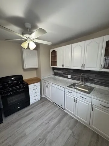 a kitchen with granite countertop a stove a sink and dishwasher with wooden floor