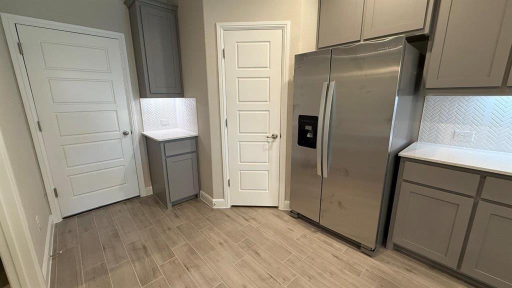 1918 Jackson Street Cleburne, TX 76033 - Photo 1 of 20 a view of a refrigerator in kitchen and an empty room with wooden floor