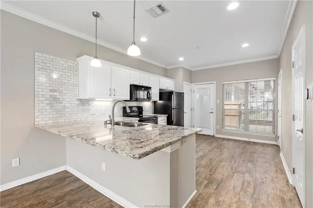 a view of a kitchen with kitchen island a sink wooden floor wooden floor and a refrigerator
