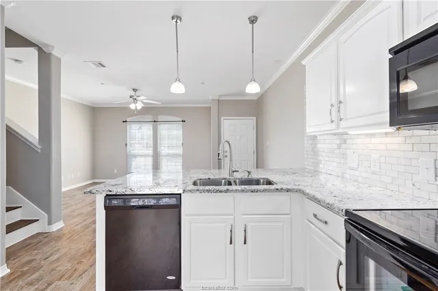 a kitchen with kitchen island granite countertop a sink a counter space appliances and cabinets