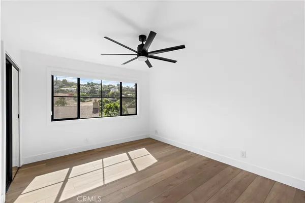an empty room with wooden floor and windows