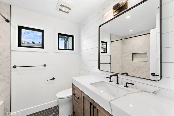 a bathroom with a sink a toilet and mirror
