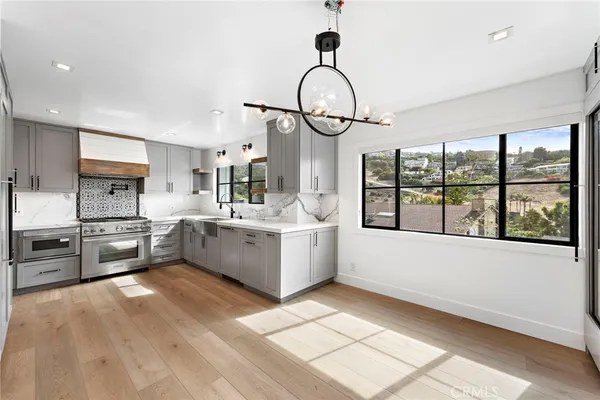 a large white kitchen with a large window and stainless steel appliances