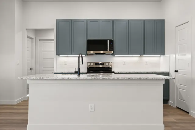 a kitchen with a sink a microwave a refrigerator and cabinets