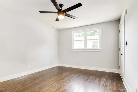 an empty room with wooden floor fan and windows