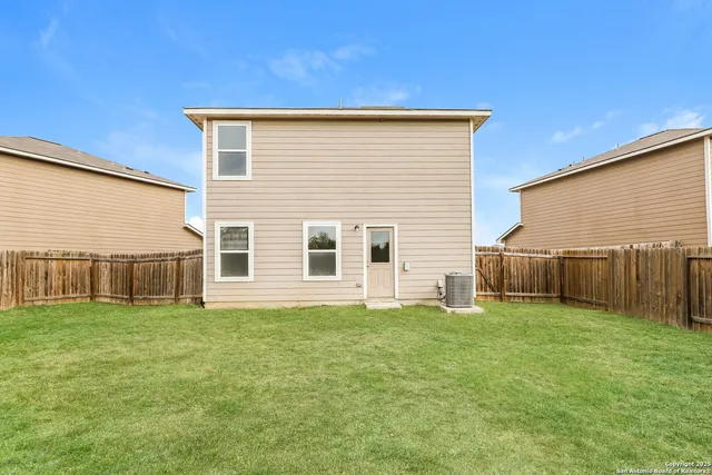 a view of a house with a yard and fence