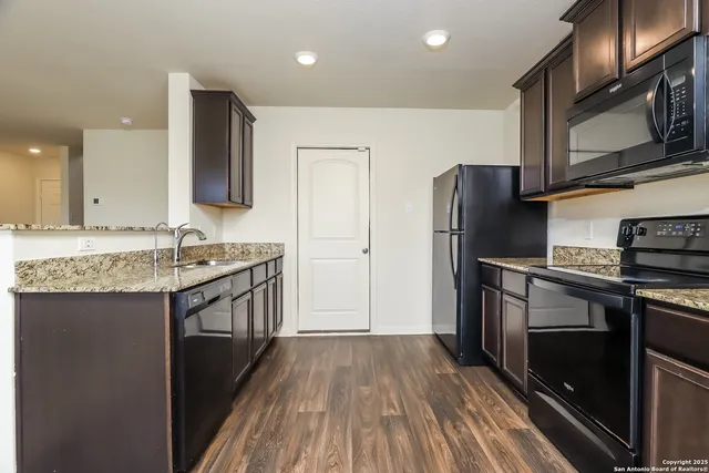 a kitchen with granite countertop a refrigerator stove and sink