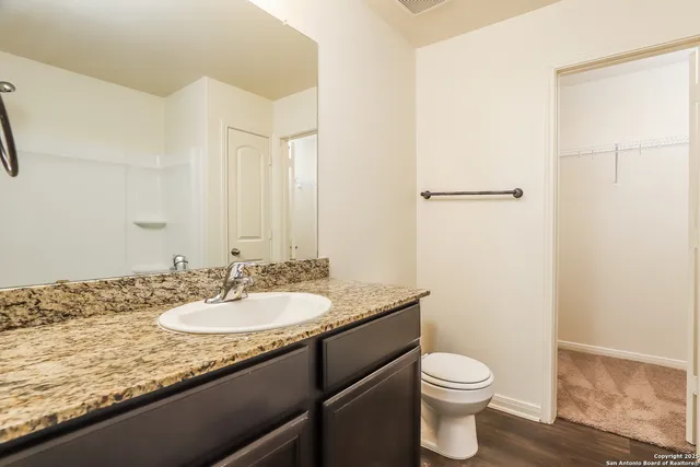 a bathroom with a granite countertop sink a toilet and a mirror