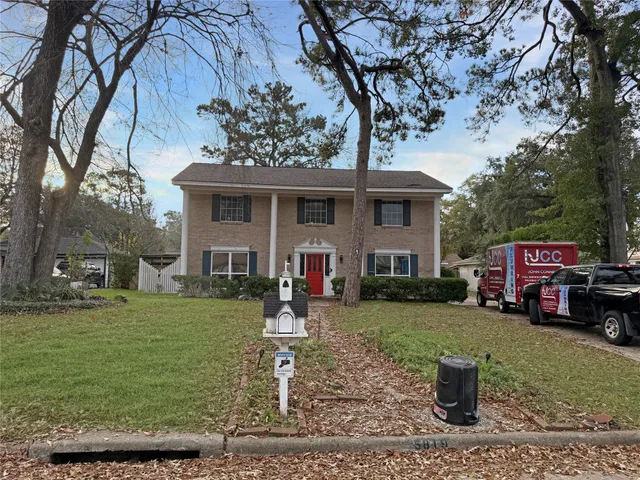 a front view of a house with garden and trees