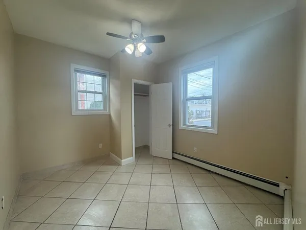 a view of an empty room with window and chandelier fan