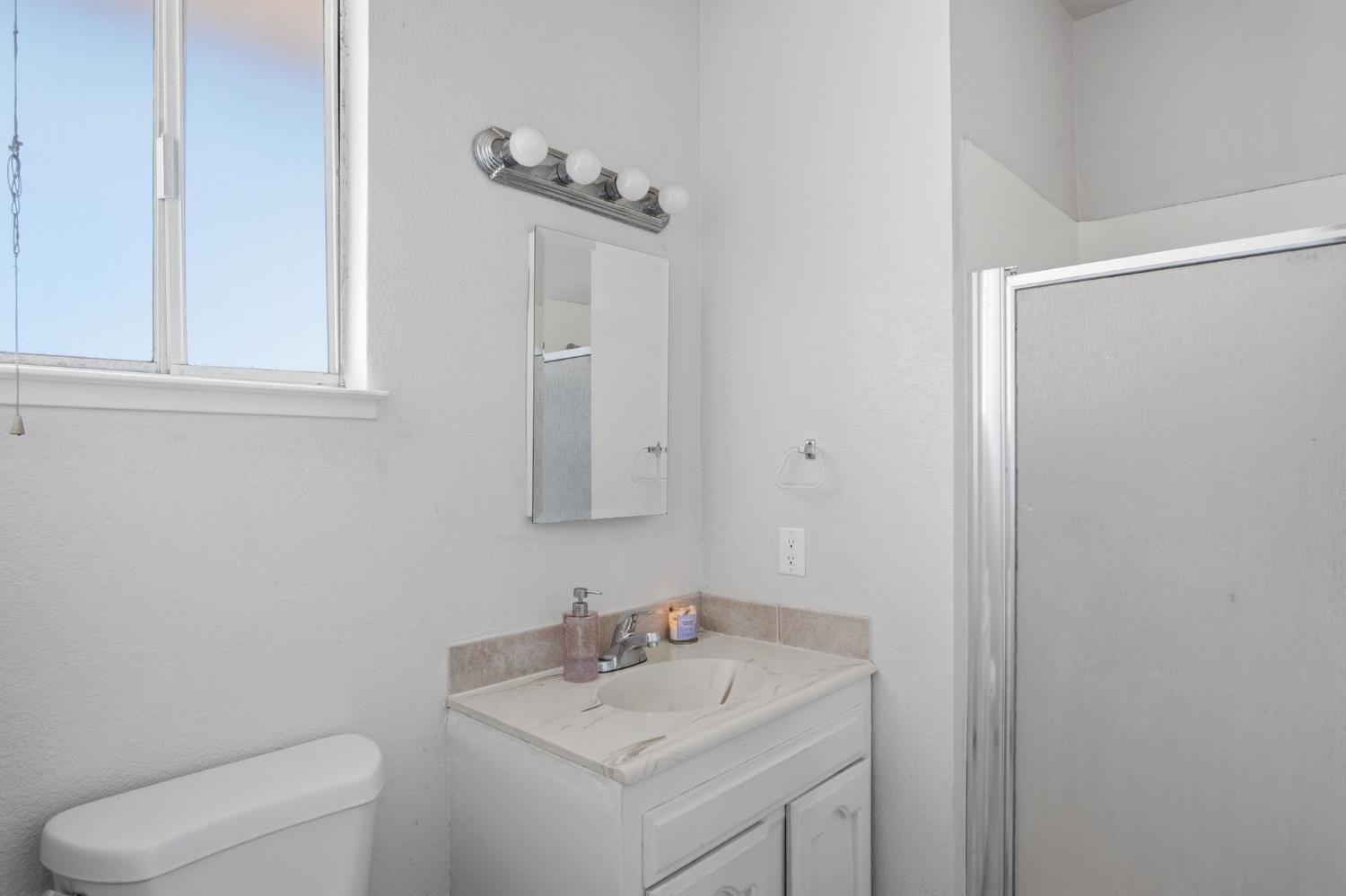 6176 Fleming Road Atwater, CA 95301 - Photo 20 of 41 a bathroom with a toilet sink vanity and mirror