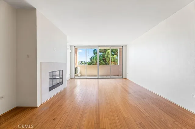 an empty room with wooden floor and fireplace