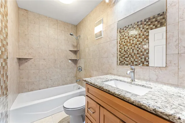 a bathroom with a granite countertop sink a toilet and bathtub