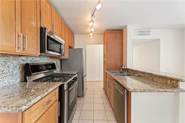 a kitchen with granite countertop a sink stove and refrigerator