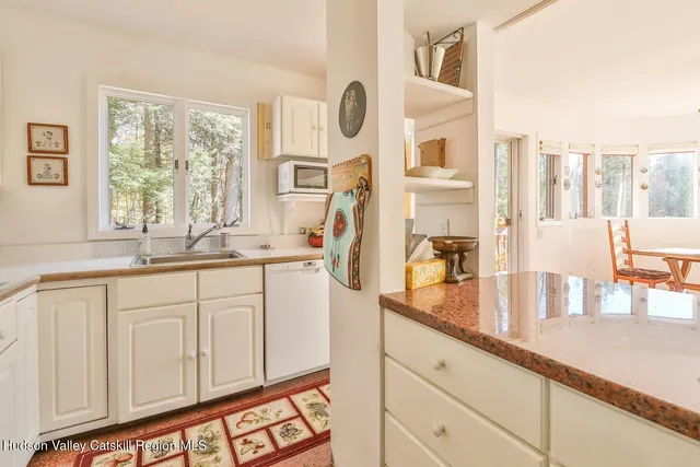 a bathroom with a granite countertop sink and a large mirror next to a window