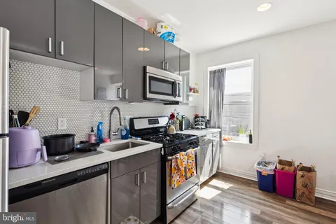 a kitchen with stainless steel appliances a sink dishwasher stove top oven and cabinets with wooden floor