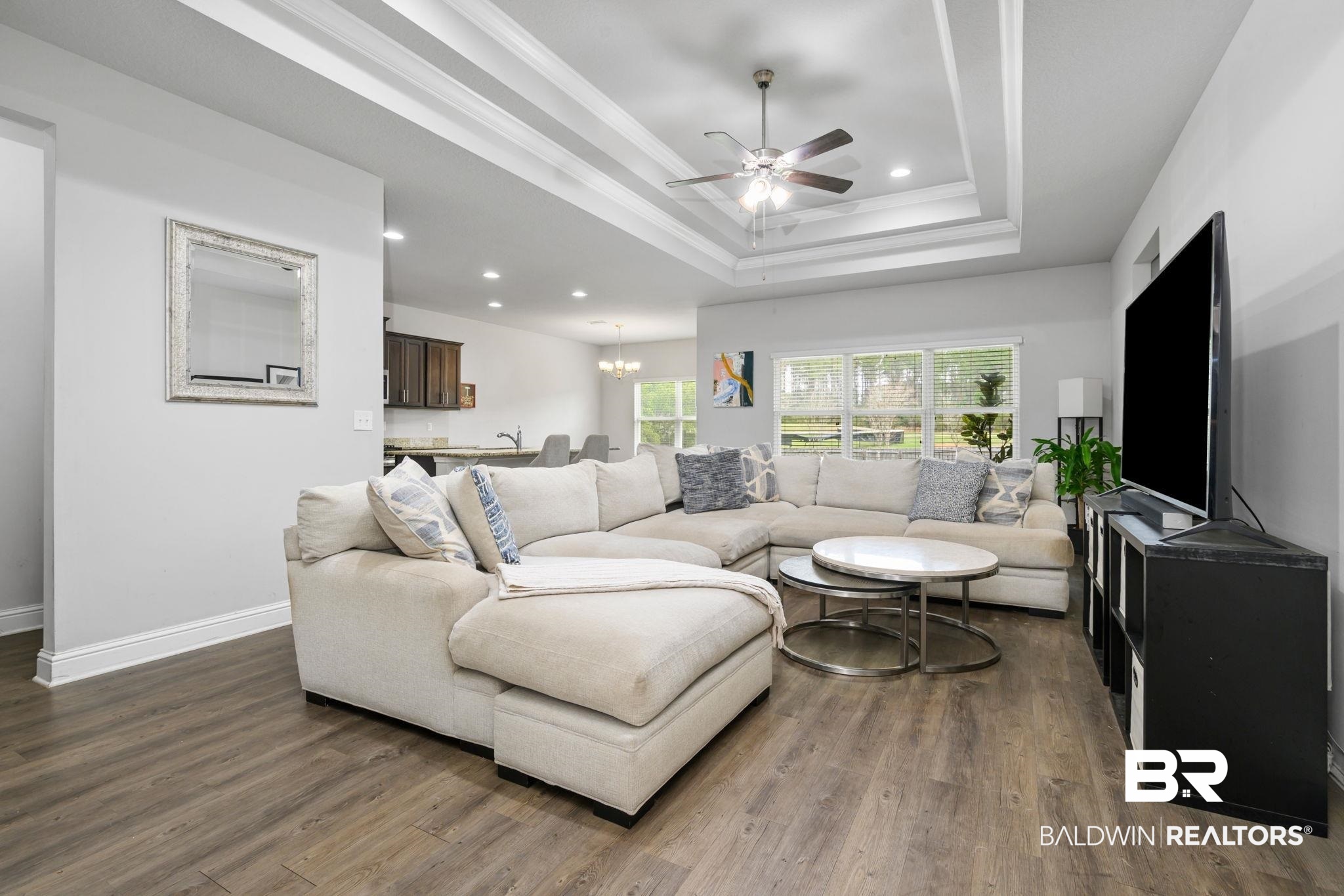 12693 Waxwing Avenue Daphne, AL 36527 - Photo 15 of 43 Living room with ceiling fan, dark wood-style floors, ornamental molding, and a chandelier