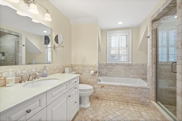 a bathroom with a double vanity sink toilet mirror and bathtub