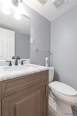 a bathroom with a granite countertop toilet sink mirror and vanity