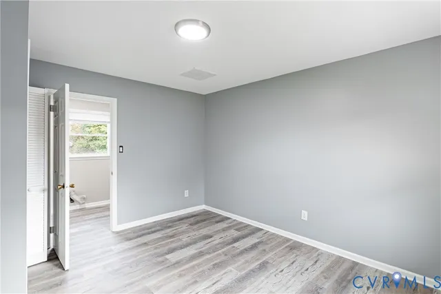 an empty room with wooden floor and a window