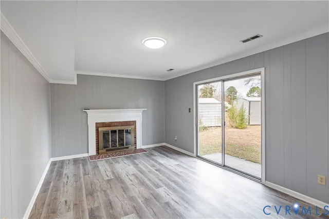 an empty room with wooden floor fireplace and windows