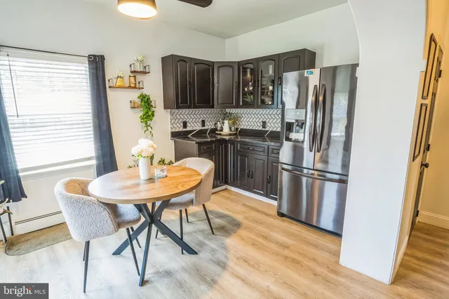 a kitchen with stainless steel appliances a refrigerator a stove a dining table and chairs with wooden floor