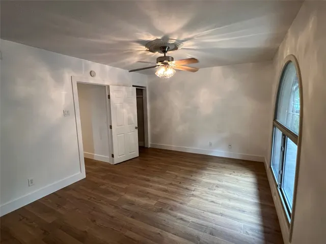an empty room with wooden floor and a ceiling fan