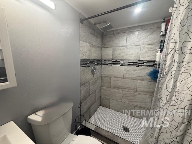 111 East Simplot Boulevard Caldwell, ID 83605 - Photo 17 of 17 Tiled shower enclosure featuring a mosaic accent band, ceiling-mounted shower head, and small hexagonal floor tiles