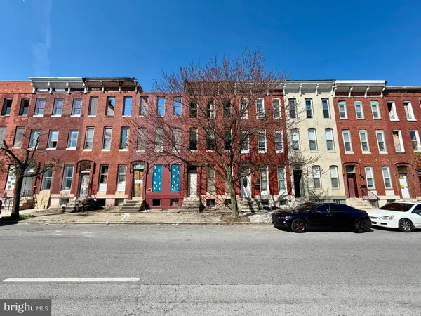 a front view of a building with lot of cars and trees