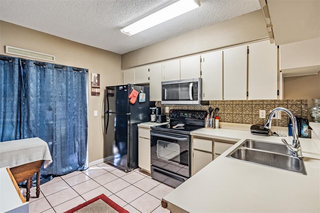 6338 Spring Flower Drive, Unit 21 New Port Richey, FL 34653 - Photo 11 of 35 a kitchen with stainless steel appliances a stove a sink a microwave a refrigerator and cabinets