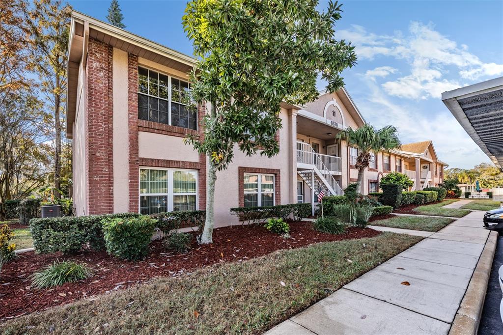6338 Spring Flower Drive, Unit 21 New Port Richey, FL 34653 - Photo 23 of 35 a view of a brick house with many windows plants and large tree