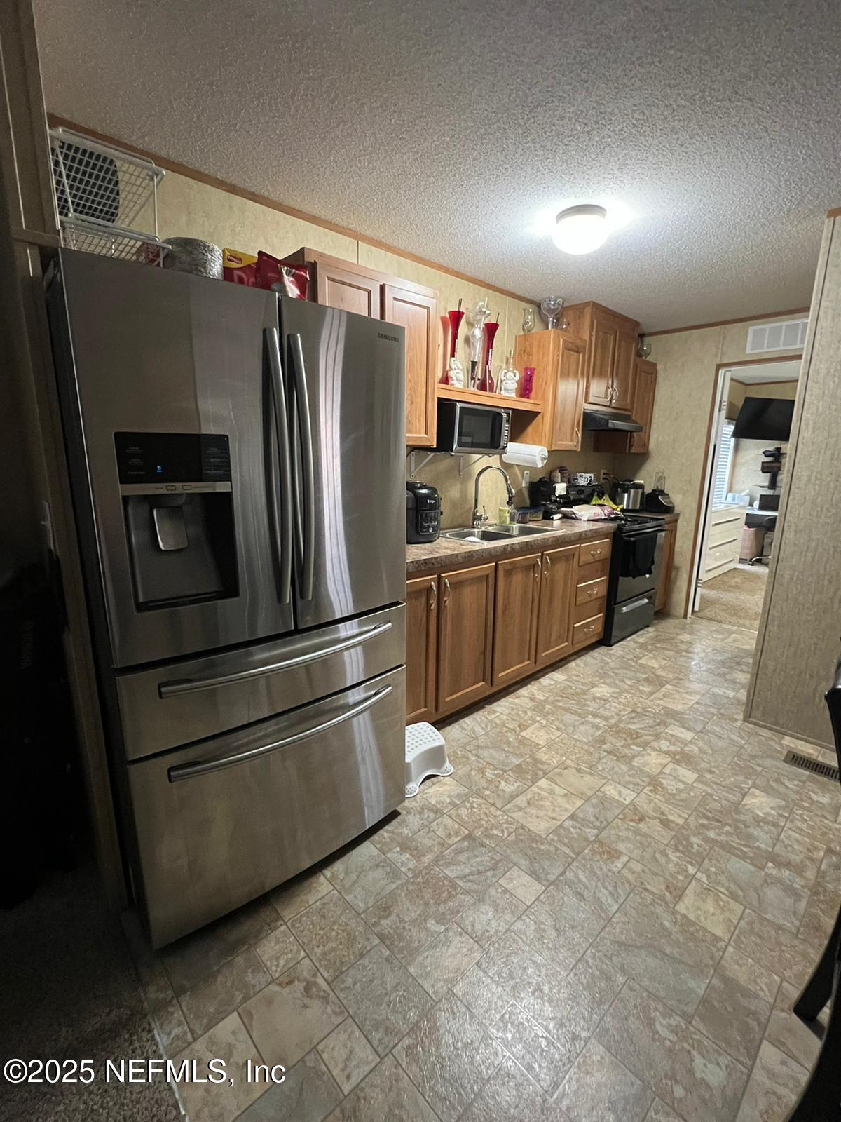 1730 Church Street Grand Ridge, FL 32442 - Photo 7 of 8 a kitchen with stainless steel appliances granite countertop a refrigerator and a stove top oven