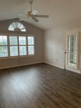 an empty room with wooden floor chandelier and windows