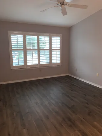 an empty room with wooden floor and windows