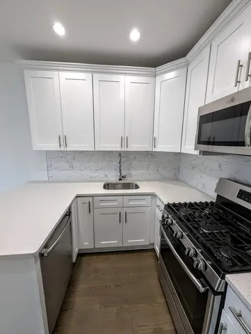 a kitchen with stainless steel appliances granite countertop a stove a sink and a microwave