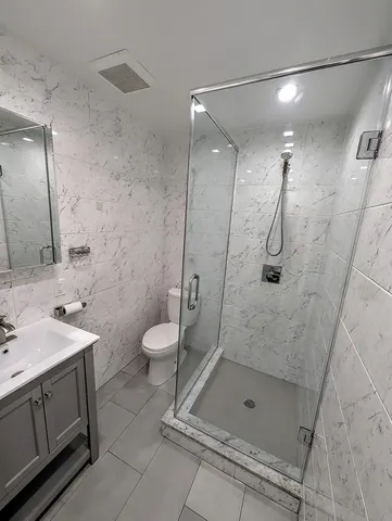 a bathroom with a shower sink mirror and toilet