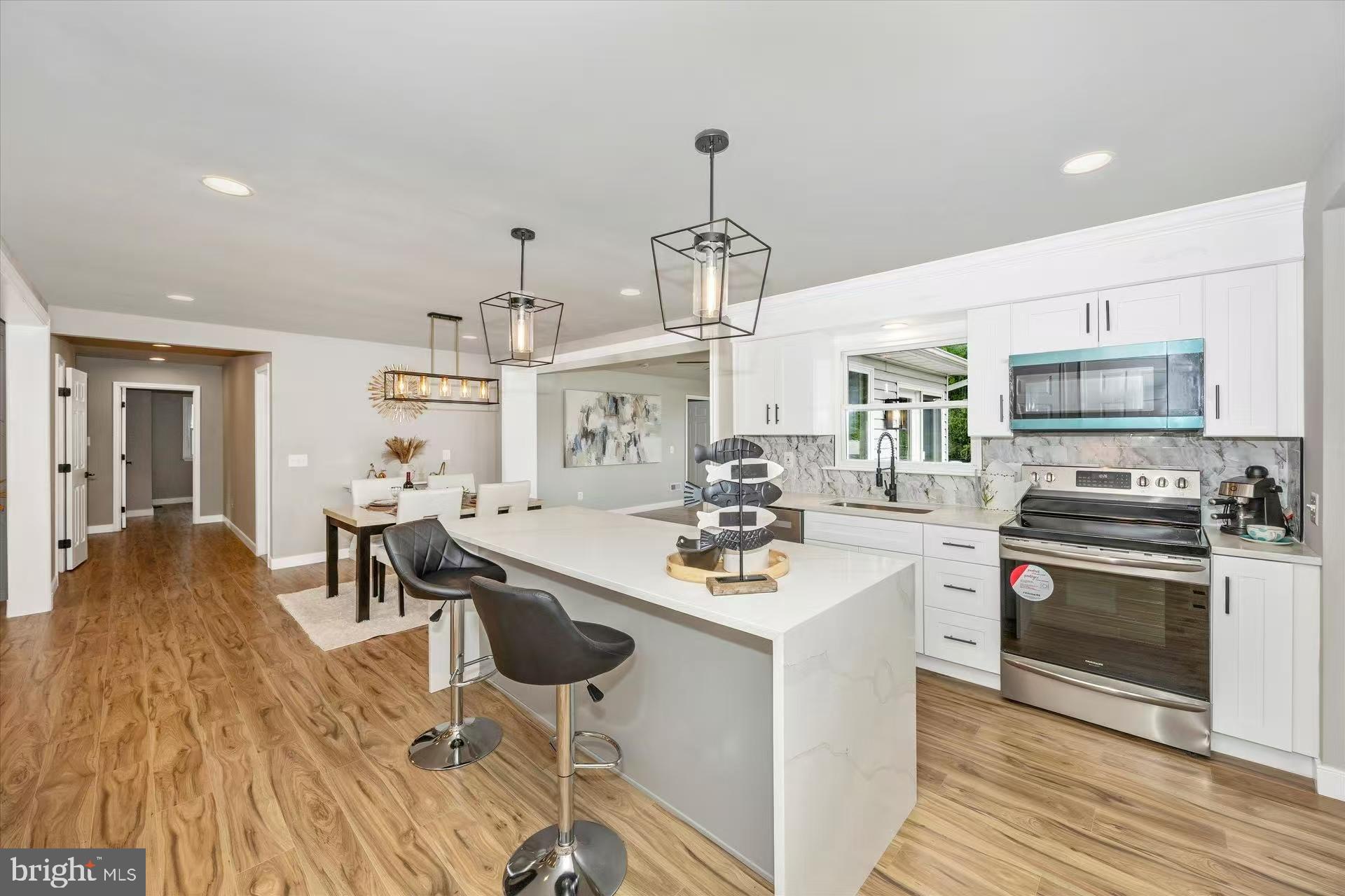 1212 Random Ridge Road Westminster, MD 21157 - Photo 12 of 36 a kitchen with stainless steel appliances kitchen island granite countertop a sink stove and white cabinets with wooden floor