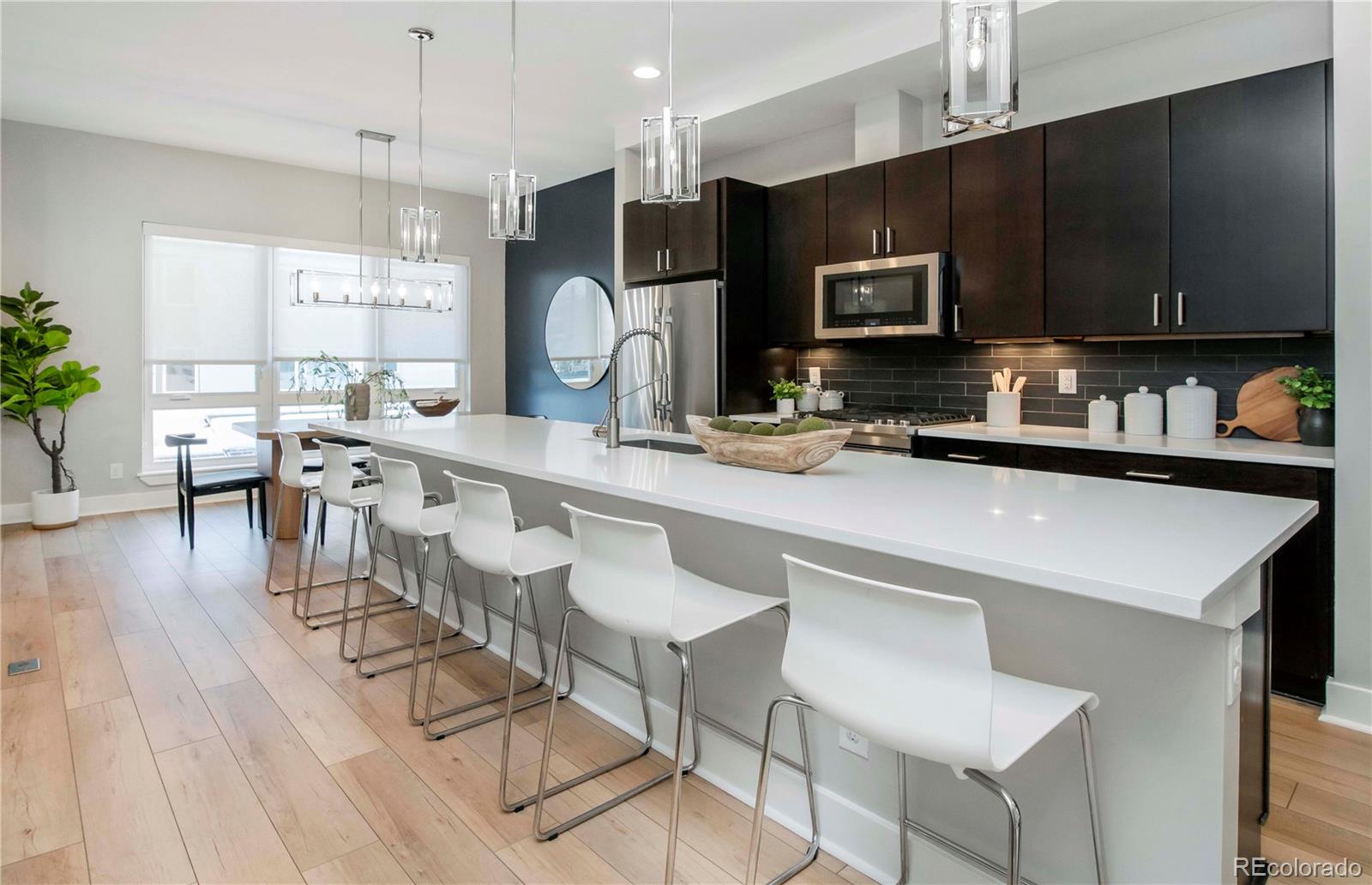 1933 Grove Street Denver, CO 80204 - Photo 11 of 29 a kitchen with stainless steel appliances a table chairs refrigerator and microwave