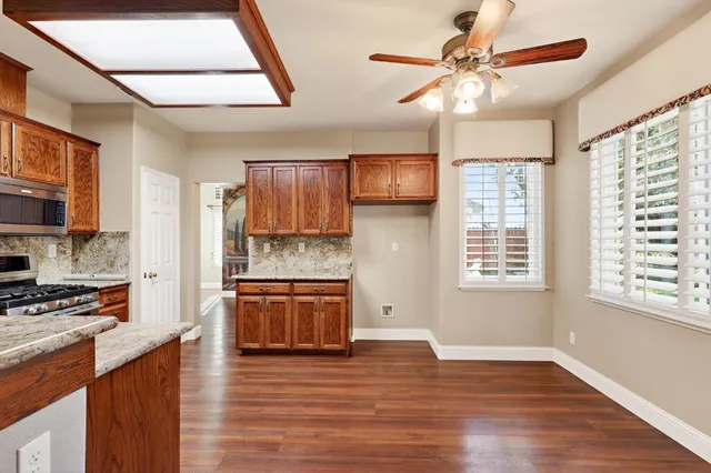 a kitchen with granite countertop wooden floors a stove a sink and a window