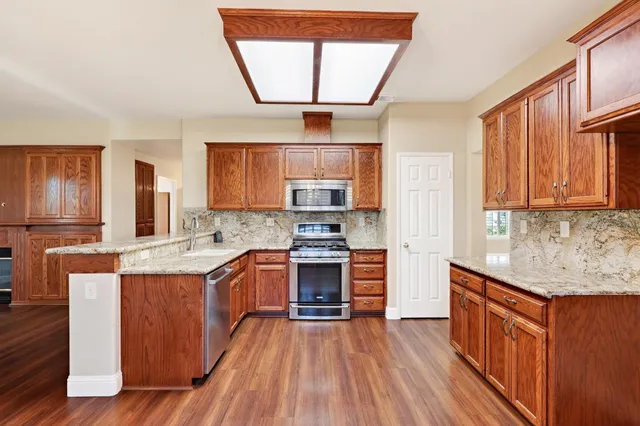 a kitchen with stainless steel appliances granite countertop wooden floors and white cabinets