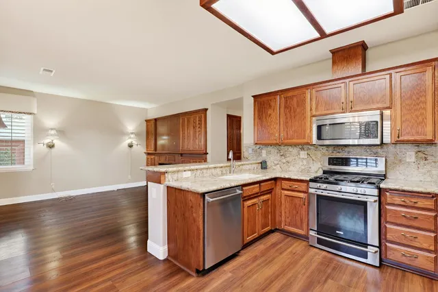 a kitchen with stainless steel appliances granite countertop wooden floors and granite counter tops