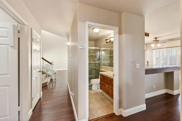 a view of a hallway with wooden floor and a bathroom