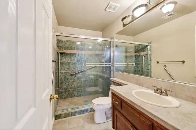 a bathroom with a granite countertop sink toilet a mirror and shower