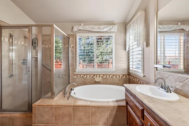 a bathroom with a granite countertop tub a sink and a large mirror