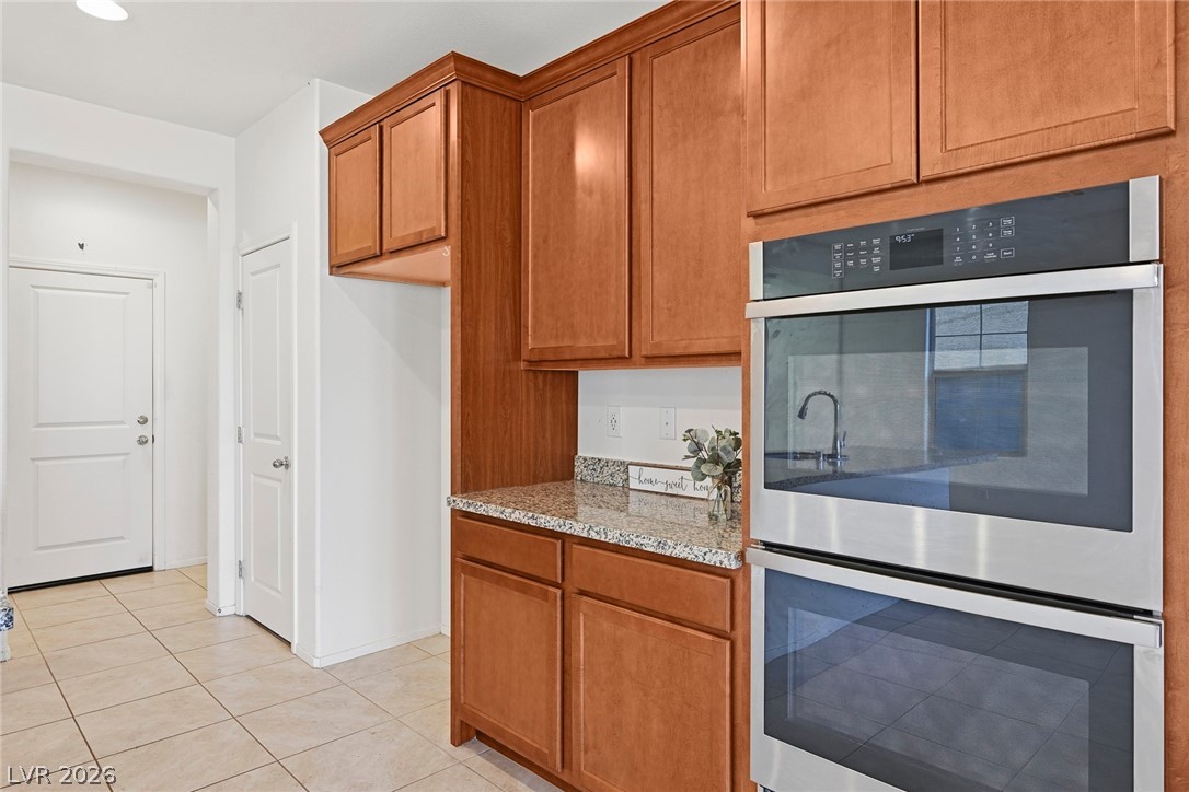 250 Dedication Avenue Henderson, NV 89011 - Photo 15 of 67 Kitchen featuring stainless steel double oven, wood finish cabinets, light stone countertops, and light tile patterned floors
