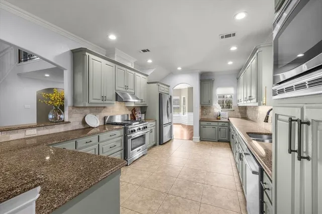 a large kitchen with stainless steel appliances lots of counter space a sink and a refrigerator