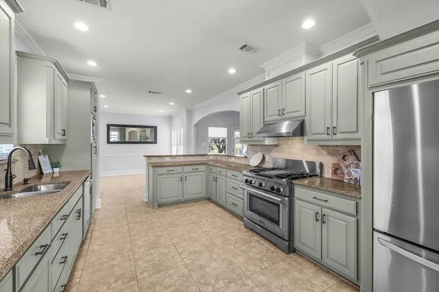 a kitchen with stainless steel appliances granite countertop a stove a sink and a refrigerator