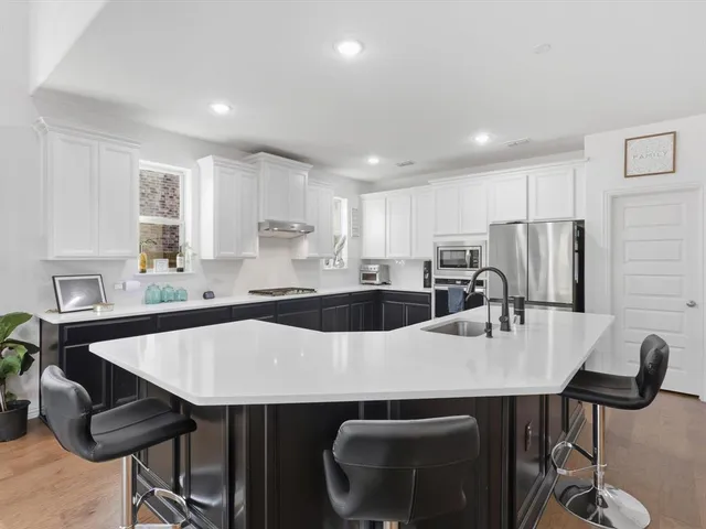 a kitchen with stainless steel appliances a table chairs microwave and sink
