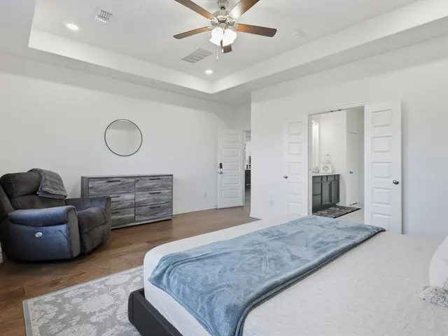 a spacious bedroom with a bed a couch and chandelier