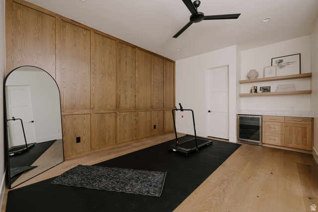 2281 South Crimson Cliffs Way St. George, UT 84790 - Photo 26 of 47 Exercise/flex area with beverage cooler, light wood-type flooring, wooden walls, a ceiling fan, and a bar